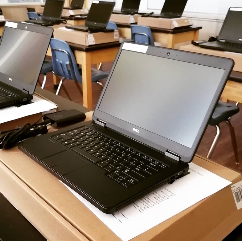 A room of Dell laptops being prepared for deployment, boxed with asset paperwork